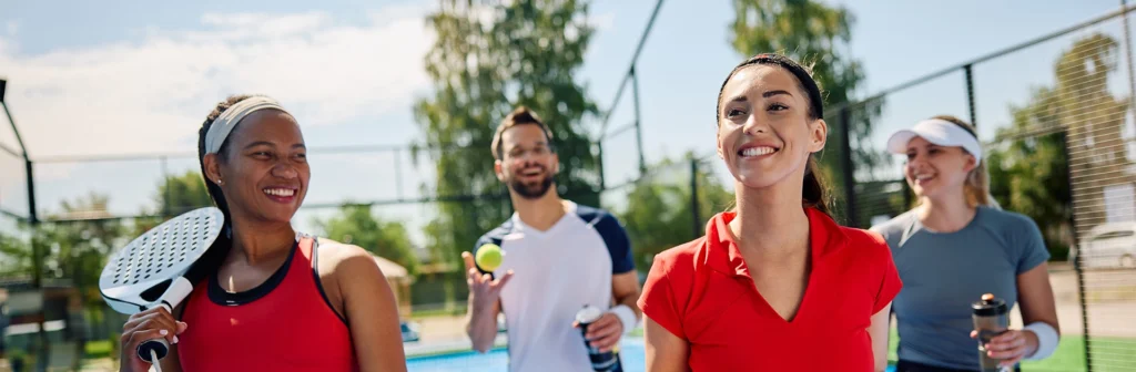 Group of Padel players smiling walking onto Padel court