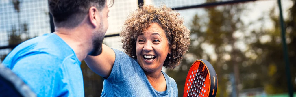 Man and woman smiling at each other whilst playing Padel